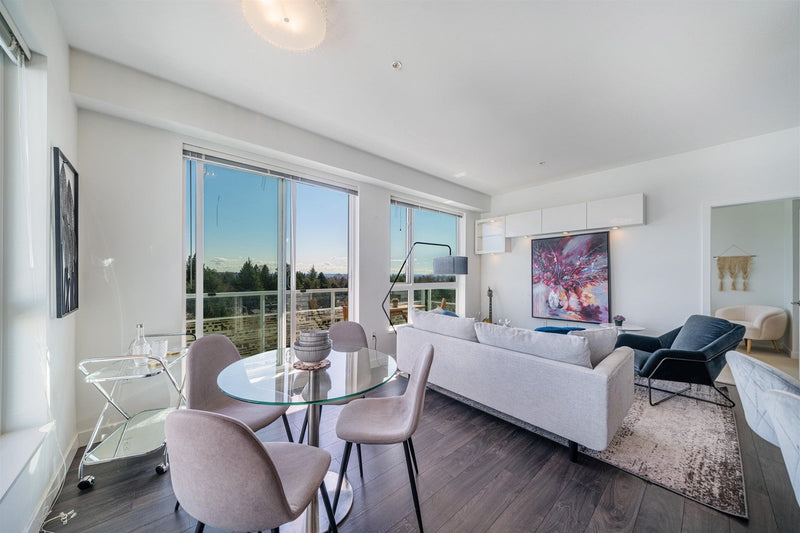 Modern living room with white sofa, glass dining table, and chairs.